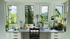 A study with a desk, chair, and multiple windows offering a view of greenery and houses. - Holiday rental Kallenbachtal I (Löhnberg)