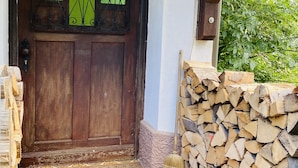 A wooden door with decorative glass panels, a wooden staircase, a doormat, and a stack of firewood. - Holiday rental Kallenbachtal I (Löhnberg)