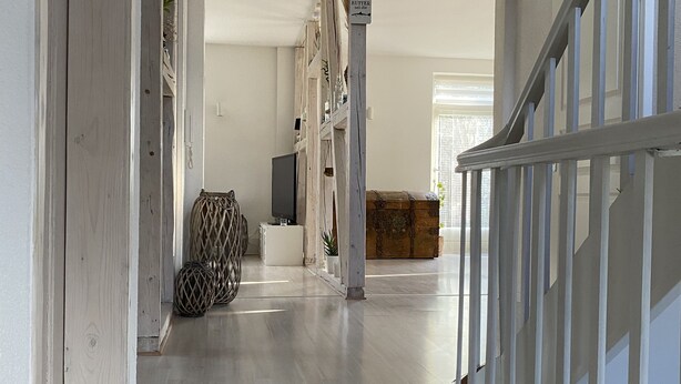 A spacious hallway with a wooden floor, a staircase on the right, and a large window at the end. - Holiday rental Kallenbachtal I (Löhnberg)