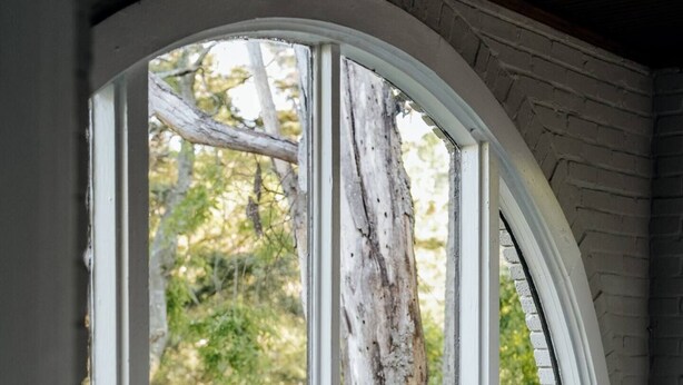 A room with a large arched window overlooking a wooded area. - Charming 2BR Getaway | Pets Welcome in Cloverdale (Montgomery)