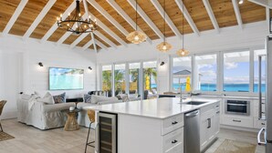 A spacious kitchen with a large island, white cabinetry, and a view of the ocean. - Casa Mary : The Ultimate Luxury Beachfront Home in the Exumas (Jimmy Hill)
