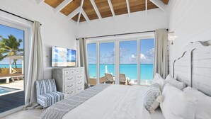 A bedroom with a large bed, a TV, and a view of the ocean. - Casa Mary : The Ultimate Luxury Beachfront Home in the Exumas (Jimmy Hill)
