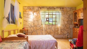 A room with a bed, a window with curtains, a stone wall, and a wooden cabinet. - Stunning home in Vallehermoso with WiFi (Vallehermoso)