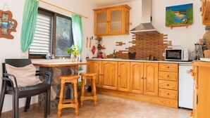 A compact kitchen with wooden cabinets, a built-in microwave, and a stone backsplash. - Stunning home in Vallehermoso with WiFi (Vallehermoso)