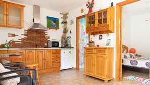 A kitchen with wooden cabinets, a microwave, and a refrigerator. There is a dining area with a table and chairs. - Stunning home in Vallehermoso with WiFi (Vallehermoso)
