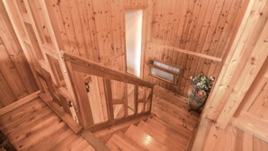 Ein Holzinnenraum mit Treppe, kleinem Fenster und einer Blumenvase.