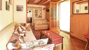 Ein gemütliches Wohnzimmer mit einer Couch, einem gemusterten Sessel und einem Holztisch mit roter Tischläufer.