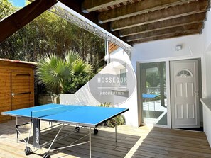 A ping pong table on a wooden deck with a white building and a door in the background. - Case du Golf - Seignosse - Pool - Golf - Beach (Seignosse)