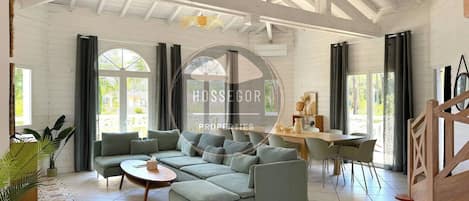 A spacious living room with a sectional sofa, a dining area, and large windows.