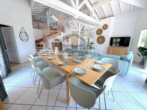 Un coin repas avec une table en bois dressée pour six personnes, entourée de chaises grises.