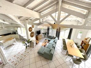 A spacious living area with a large sofa, a dining table, and a kitchen in the background. - Case du Golf - Seignosse - Pool - Golf - Beach (Seignosse)