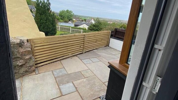 Un patio con suelo de piedra y valla de madera.