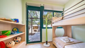 A room with bunk beds, a shelf with sports equipment, and a door leading outside. - Fluo Seaside Apartment (Aegina)