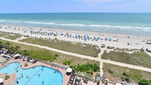 A beach resort with a swimming pool, beach umbrellas, and a clear view of the ocean.