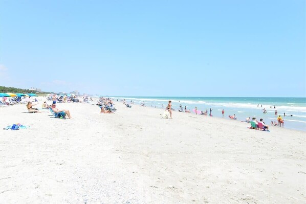 Una playa concurrida donde la gente se toma el sol y nada.
