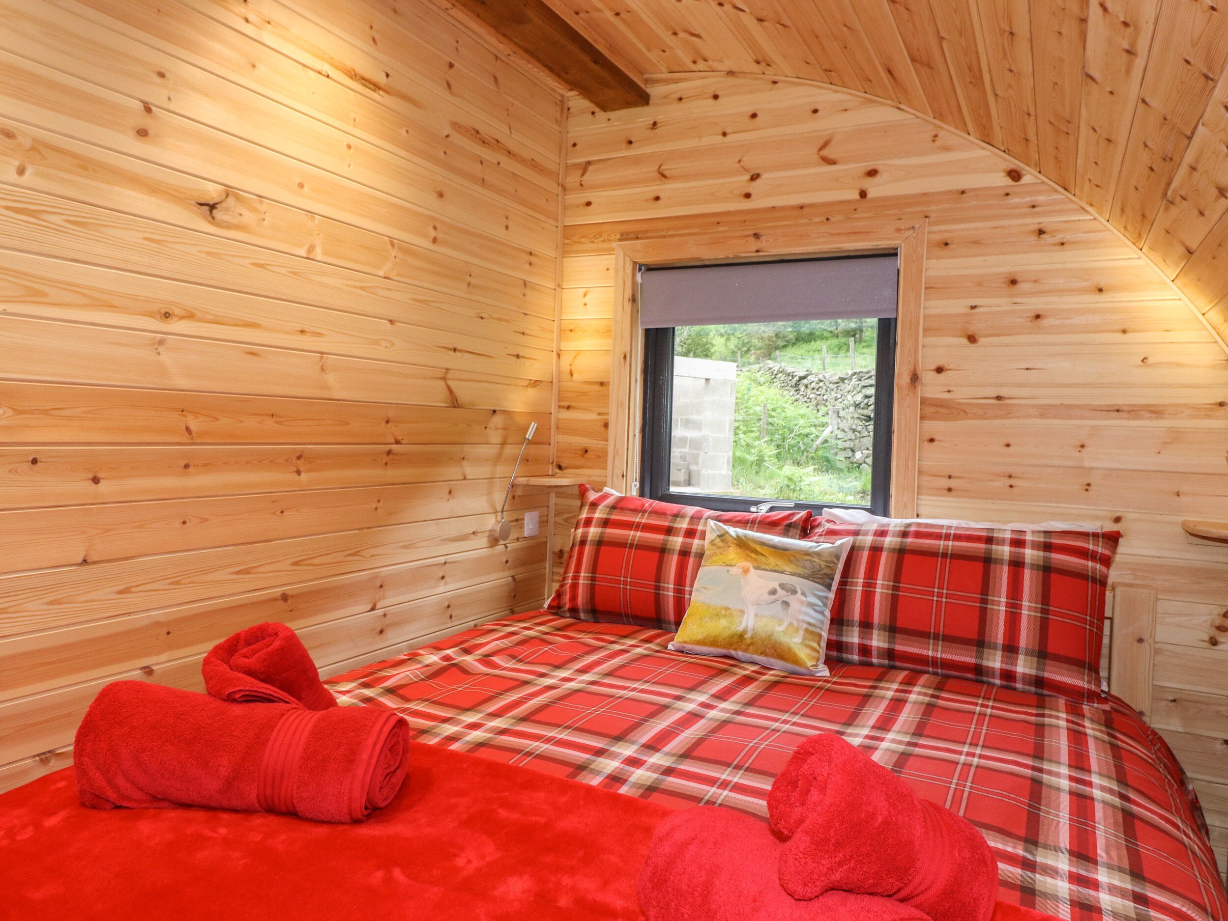 Une pièce chaleureuse, aménagée dans un chalet en bois, avec un lit, une fenêtre et une vue sur la verdure environnante.
