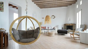 A spacious living room with a hanging chair, a fireplace, and a dining area. - Villa Super Two (Mykonos)