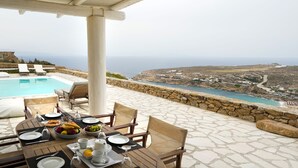 A table set for breakfast with a view of the sea and a pool. - Villa Super Two (Mykonos)