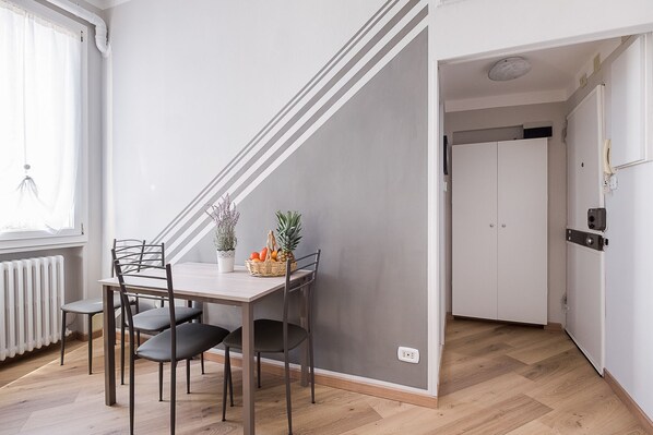 A modern kitchen with a dining area, featuring a white refrigerator, a built-in oven, and a wooden floor.