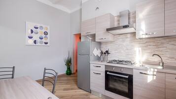 Et moderne køkken med spisebord, stole, køleskab, komfur, ovn og et backsplash.
