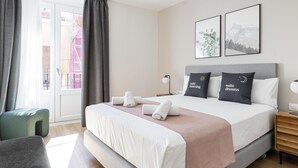 A modern hotel room with a large bed, a bedside table, a chair, and a window with curtains. - Limehome Madrid C. de Fomento (Madrid)