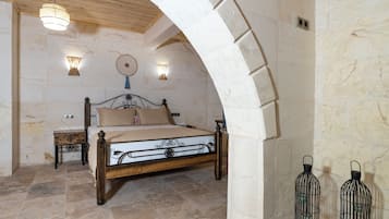 Une chambre à coucher avec un lit en bois, des murs en pierre et deux lampes fixées au mur.