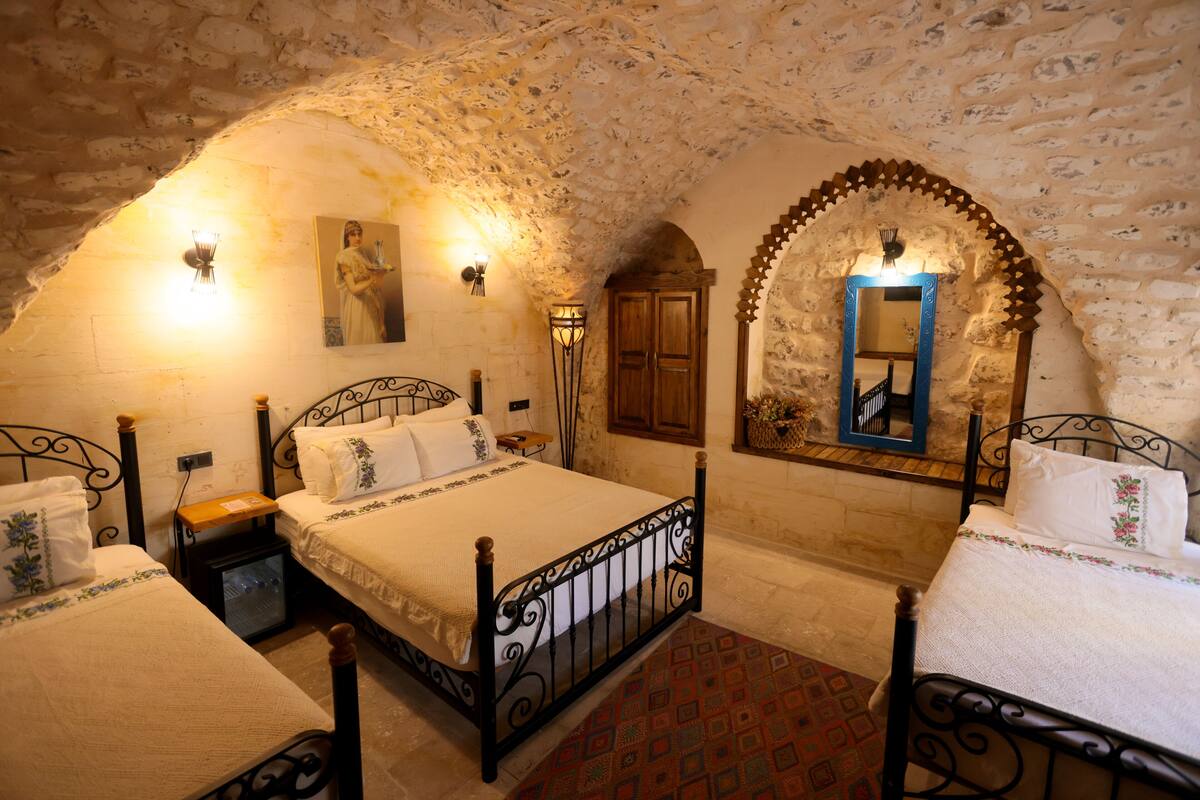 A bedroom with two beds, a wooden cabinet, and a mirror.