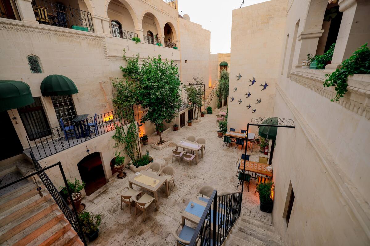 A courtyard with outdoor seating, potted plants, and a staircase.