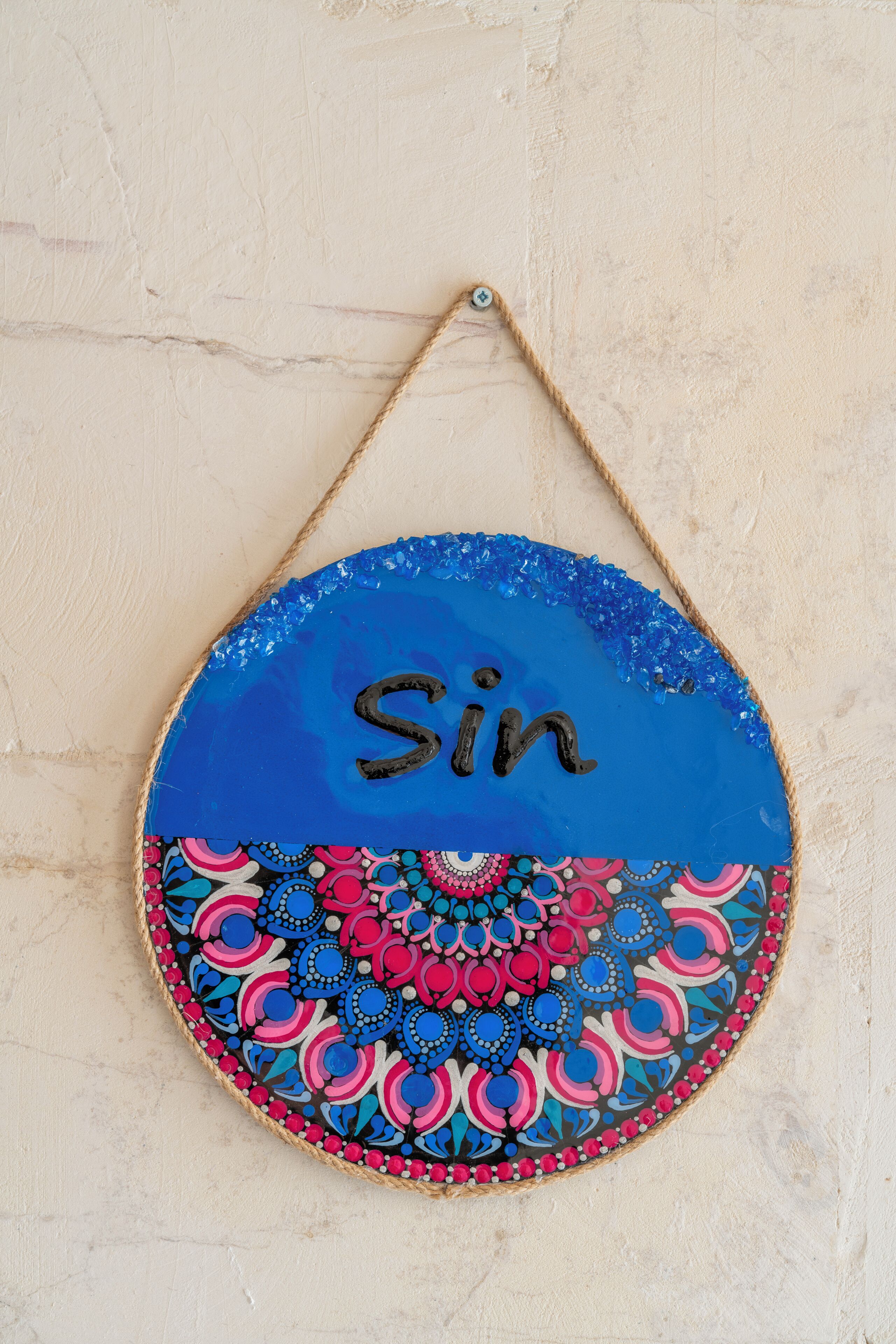 A round, wall-mounted decoration with a blue top and a colorful mandala pattern at the bottom.