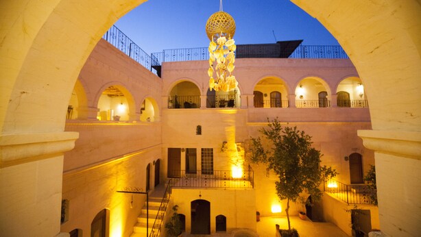 Un patio de varios niveles con arcos, un adorno esférico colgante y una escalera.