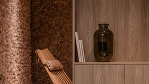 A spa room with a wooden bench, a stone wall, and a wooden cabinet with a vase. - Plantonia (Kraków)