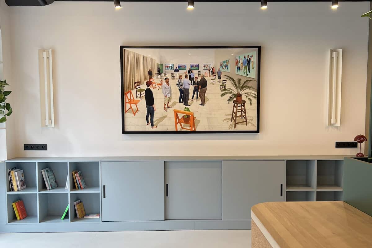 A modern interior with a large artwork, a reception desk, and a bookshelf.