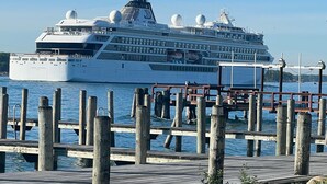 Een groot cruiseschip aangemeerd aan een steiger met een houten looppad naar het water.