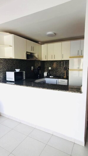 Enjoy cooking in this well-equipped kitchen with a granite countertop, white cabinetry, and stainless steel sink.