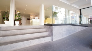 A modern hotel lobby with a reception desk, a staircase, and a glass wall overlooking the street. - Hotel Fleming Playa Poniente (Benidorm)