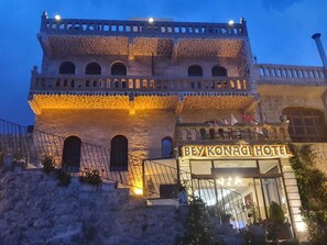 Ein Steinhaus mit einem Balkon und einem Schild mit der Aufschrift 'BEY KONAGI HOTEL'.