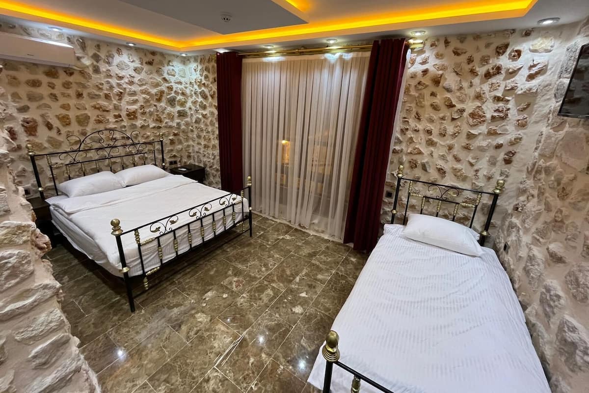 Ein Schlafzimmer mit zwei Betten, Steinwänden und einem modernen Deckenstil.