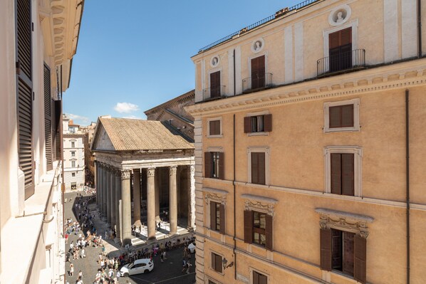 A historic building with classical architecture, including columns and a pediment, situated in a busy urban area with pedestrians and vehicles. - The Pantheon Terrace Experience (Roma)
