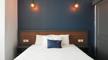 A hotel room with a bed, two bedside tables, and two wall-mounted lights.