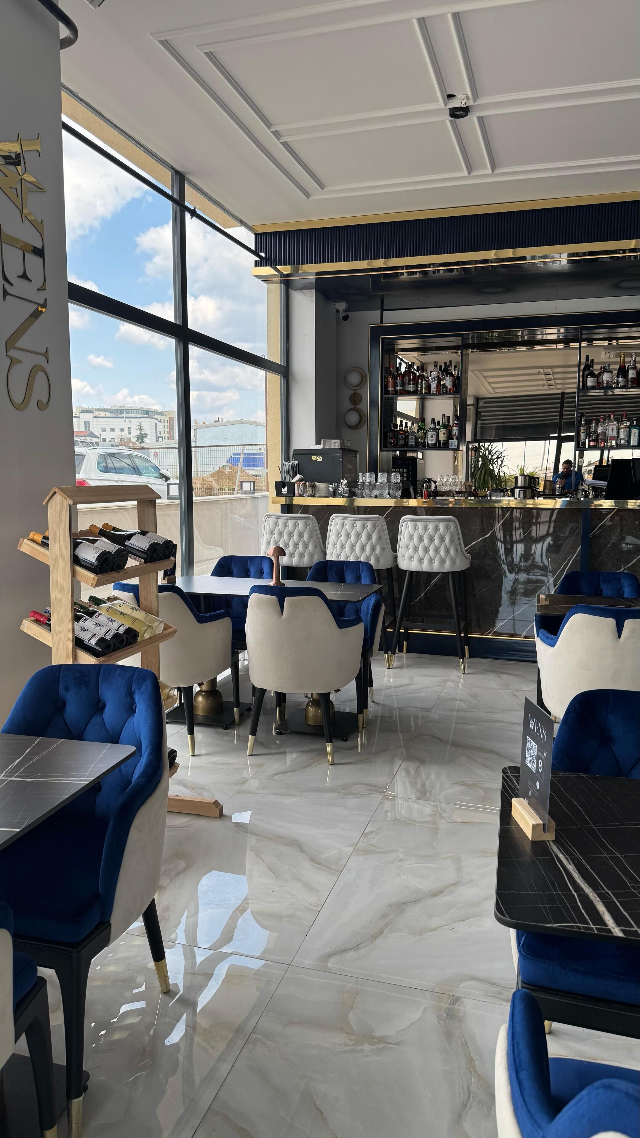 A modern bar area with a view of the city, bar stools, and a wine rack.