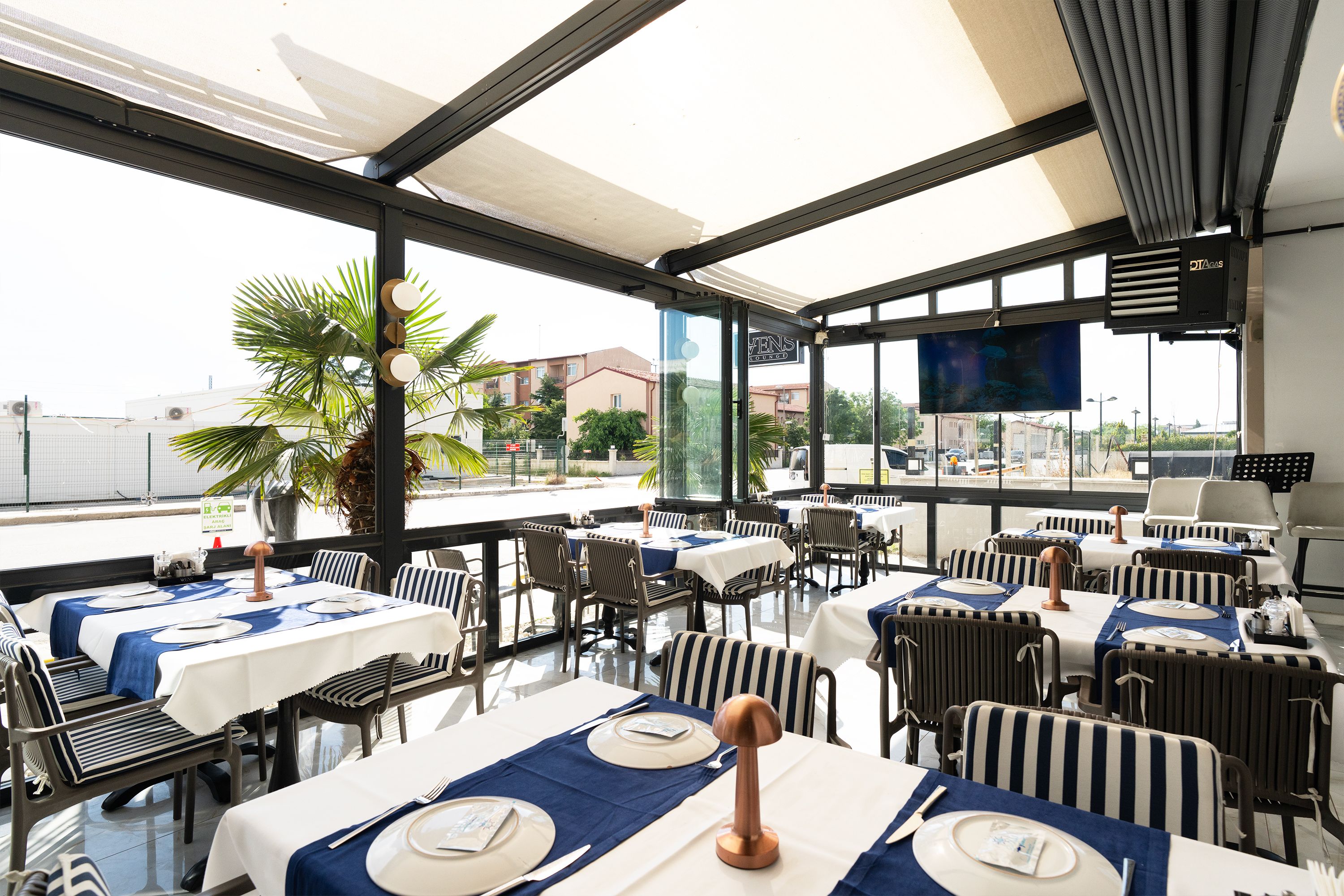 Un comedor interior con mesas dispuestas para el servicio, amplias ventanas y vistas al exterior.