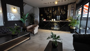 Un vestíbulo de hotel moderno con un mostrador de recepción negro, un sofá y una mesita de centro.