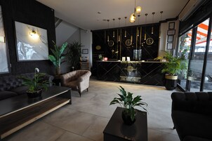 Un vestíbulo de hotel moderno con un mostrador de recepción negro, un sofá y una mesita de centro.