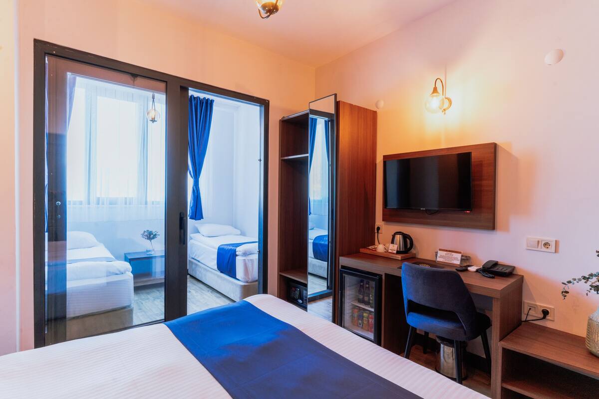 Una habitación de hotel con cama, escritorio, silla, televisor y minibar.