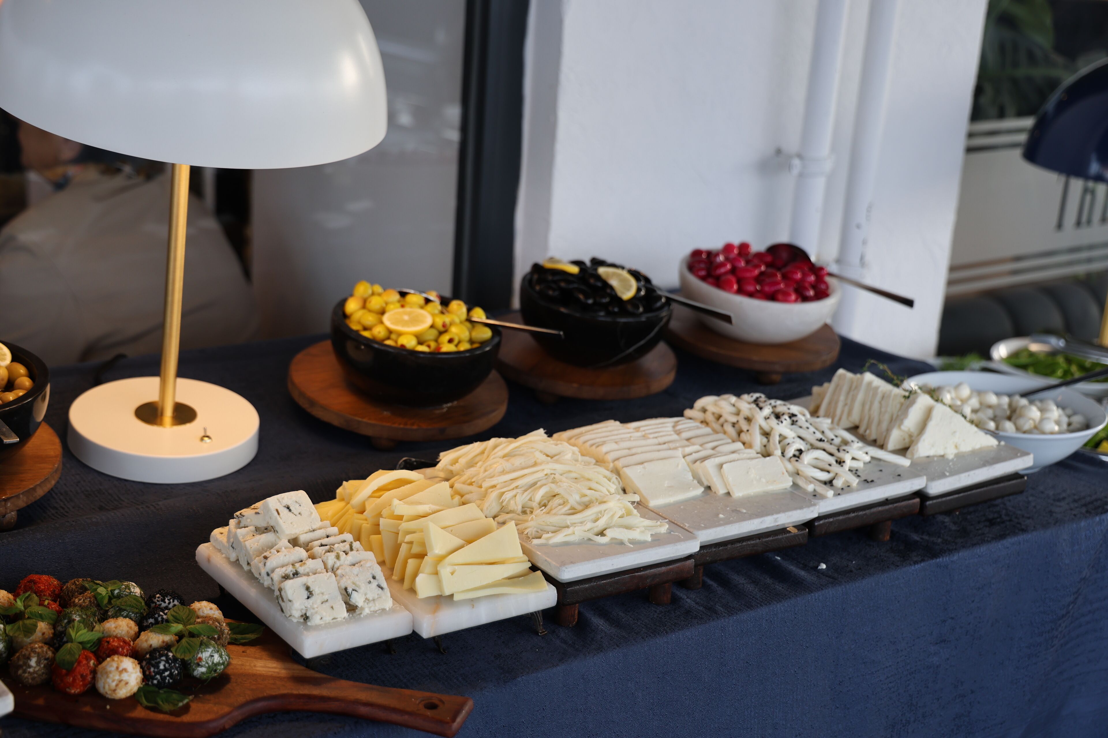 A buffet table with various cheeses, fruits, and olives.
