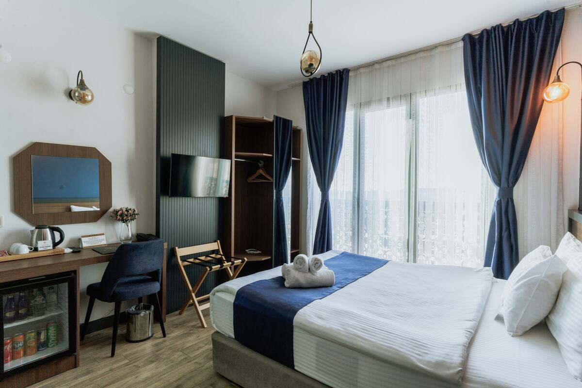 Una habitación de hotel con una cama, un escritorio, una silla, un armario y un minibar.