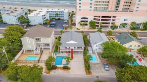 A beachfront hotel with multiple buildings, a swimming pool, and a parking area.