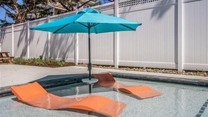 A swimming pool with two lounge chairs and a blue umbrella.