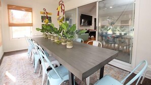 A conference room with a long table, several chairs, potted plants, a ceiling fan, and a large window.