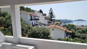 Un balcón con jacuzzi, con vistas a un pueblo costero de casas escalonadas y al mar.